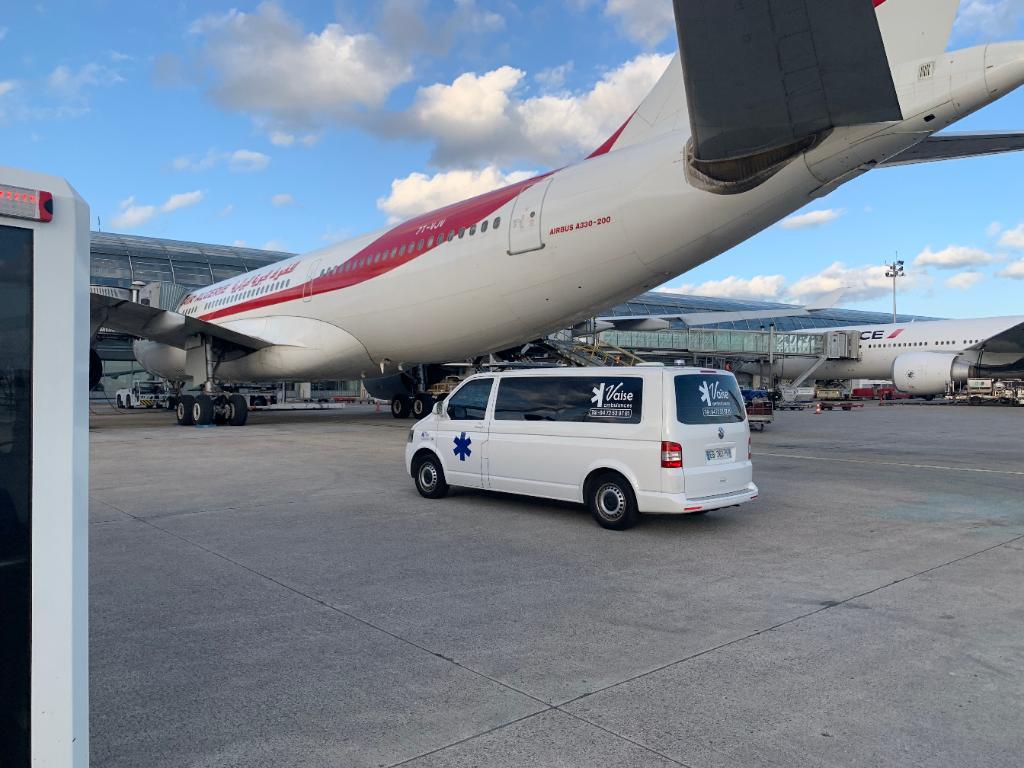 Ambulance de l'entreprise Vaise Ambulances derrière un avion dans l'aéroport