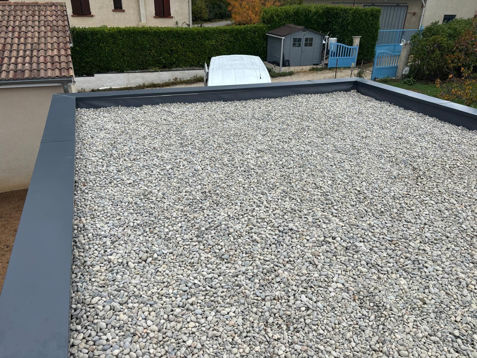 Un ouvrier en tenue de protection utilise un chalumeau à propane pour chauffer l'asphalte sur un chantier.