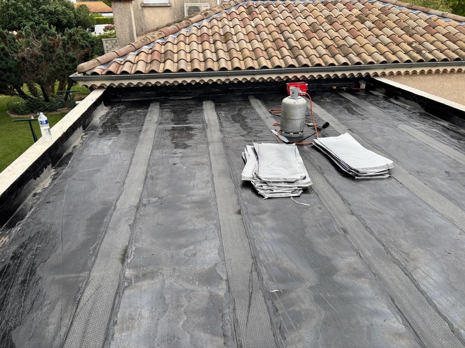 Un marteau repose sur une surface grise et rugueuse, à côté d'un récipient en plastique ouvert rempli de clous argentés.