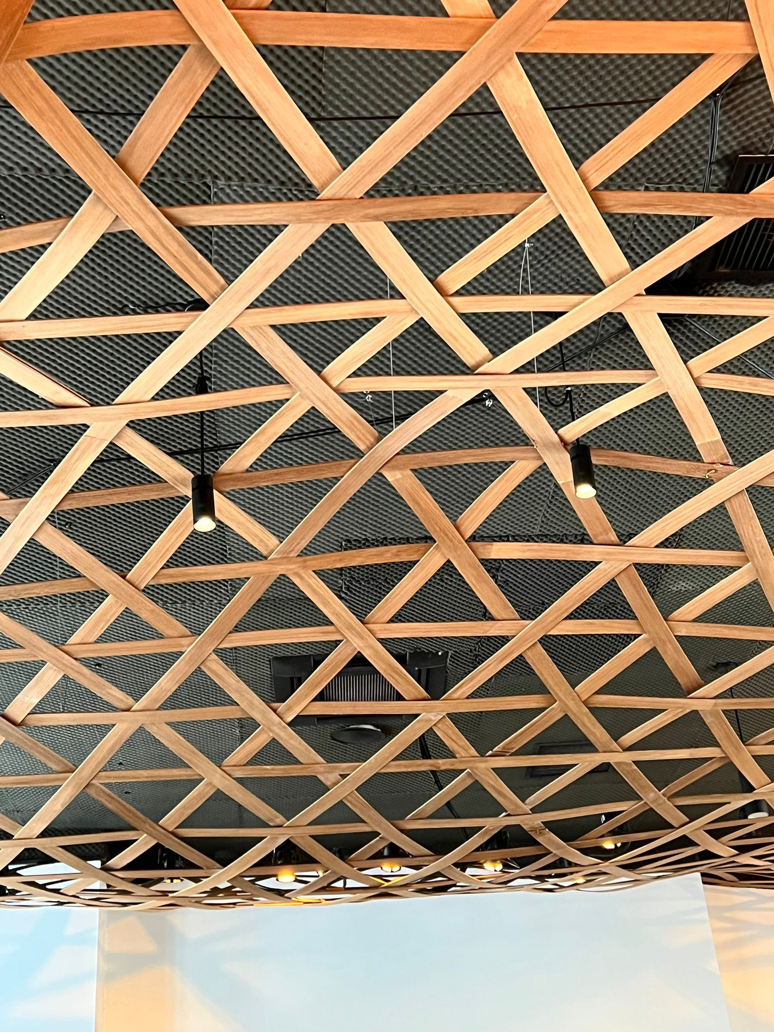Estructura de techo de celosía de madera con un atisbo del cielo azul debajo