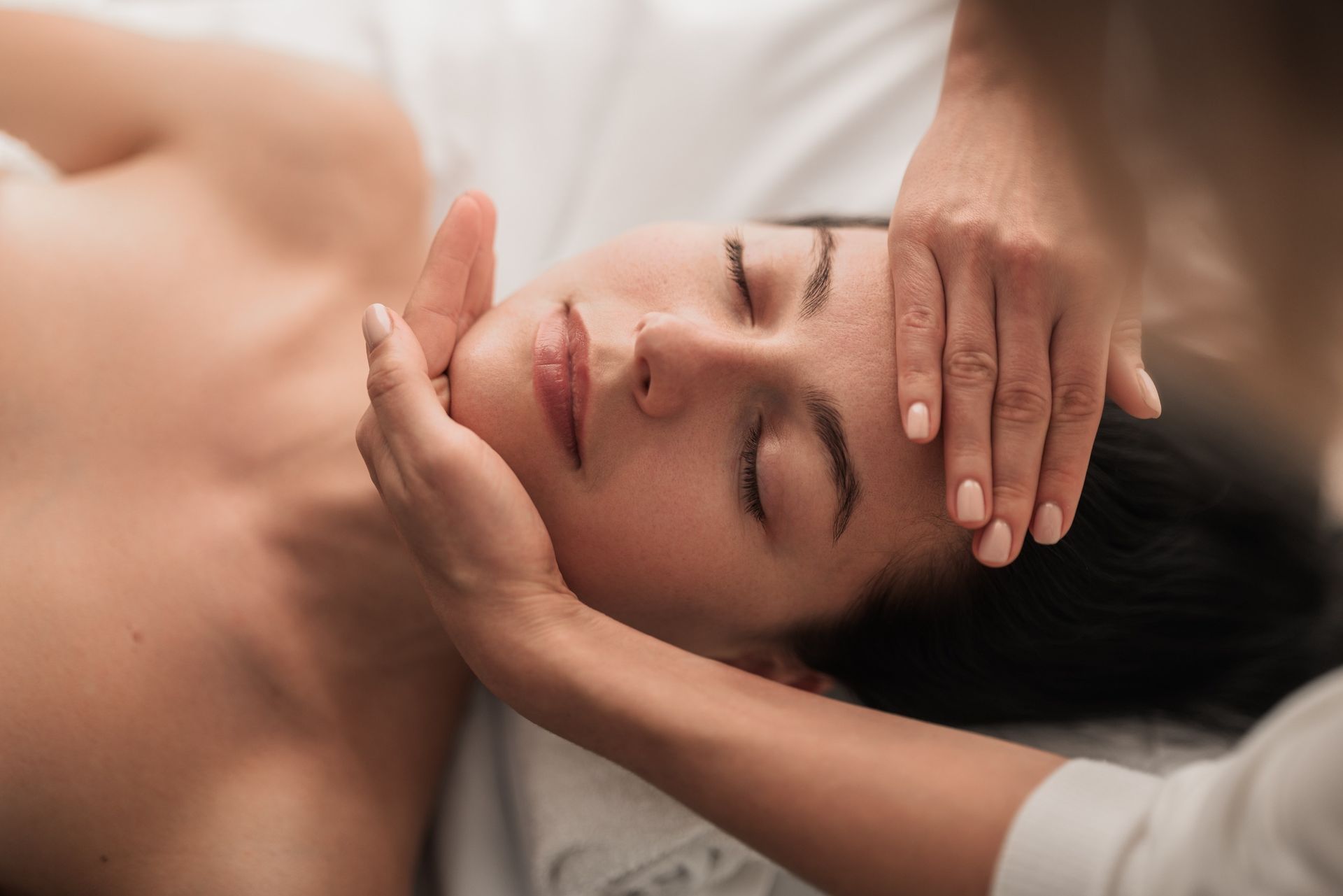 Una mujer está recibiendo un masaje de cabeza en un spa.