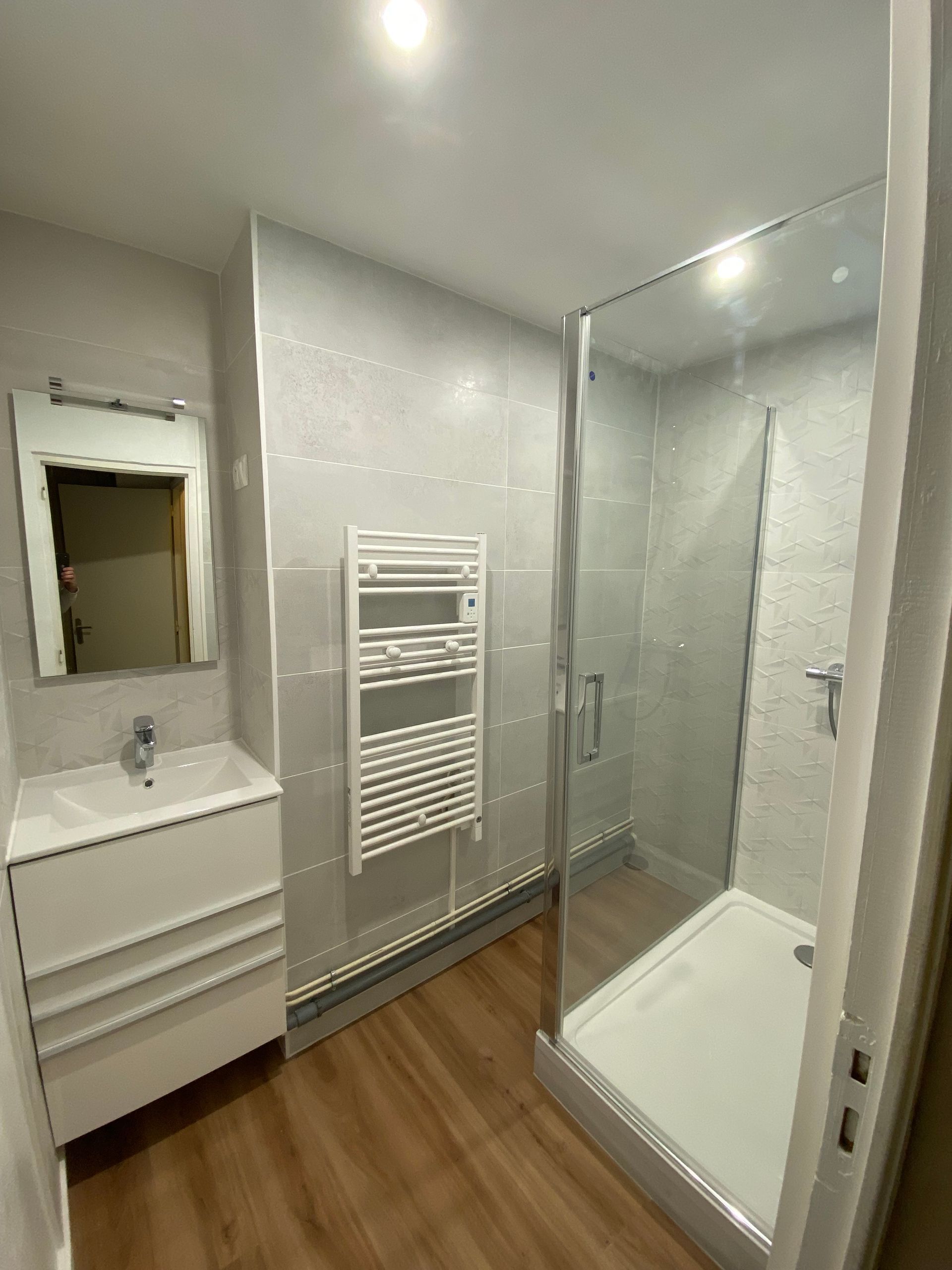 Salle de bains avec une cabine de douche et un sèche-serviettes blanc