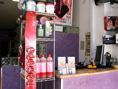 Mostrador de salón de belleza con productos para el cabello, un panel de pared morado y un mostrador de recepción de madera.