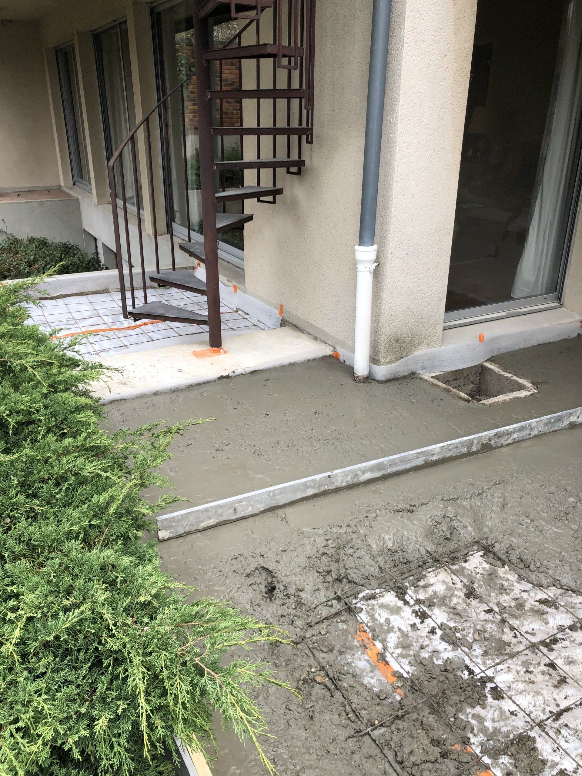 Une jeune femme aux cheveux bruns ondulés rit, les yeux fermés, vêtue d'une chemise verte sur fond blanc.