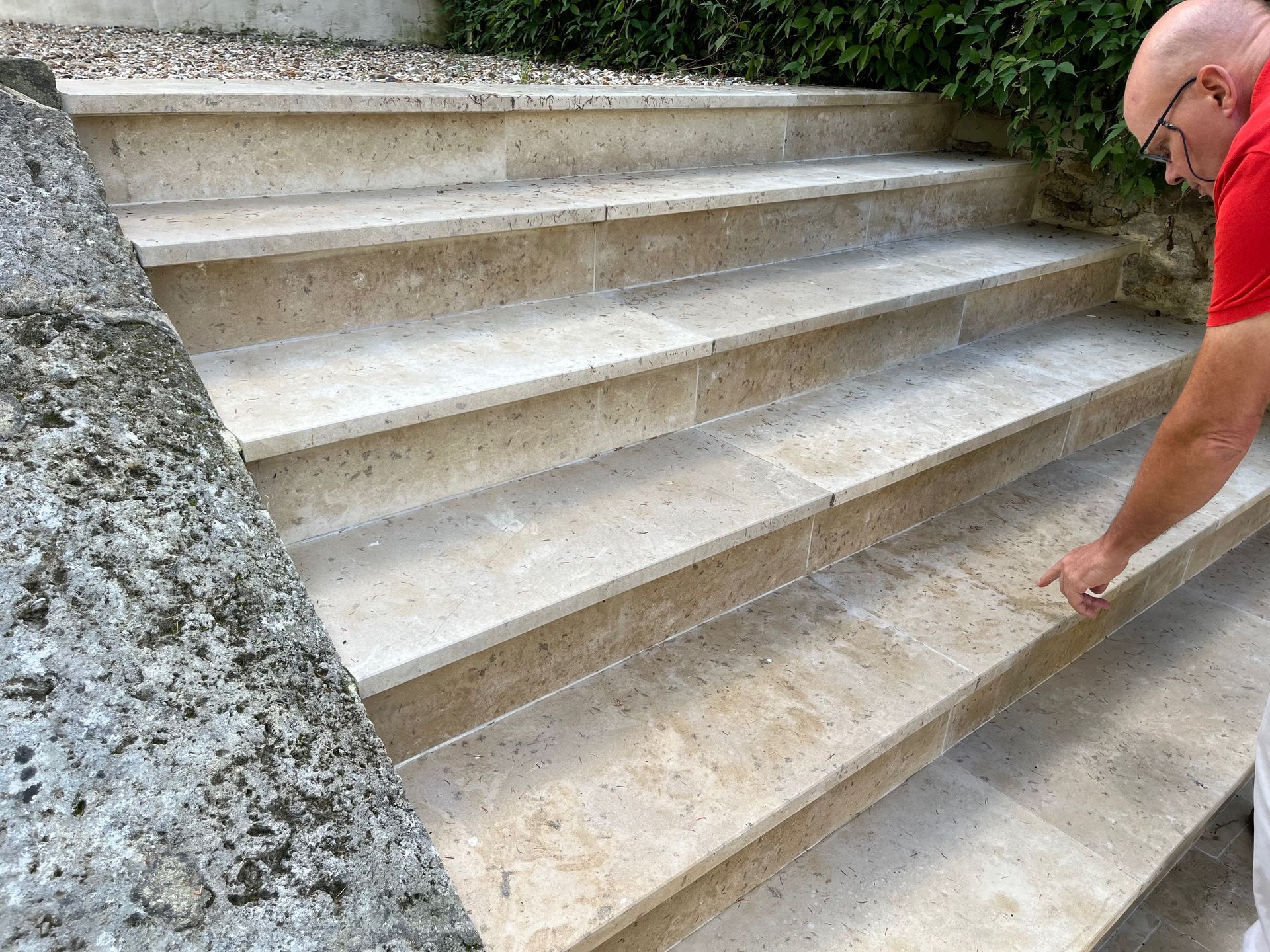 Marches en pierre avec une personne en chemise rouge pointant la marche du bas.