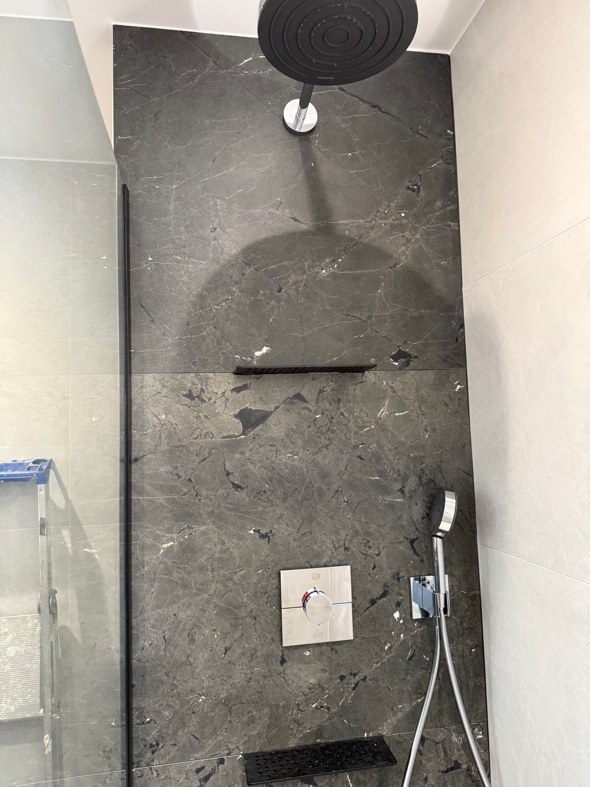 Douche moderne avec carrelage foncé et parois vitrées