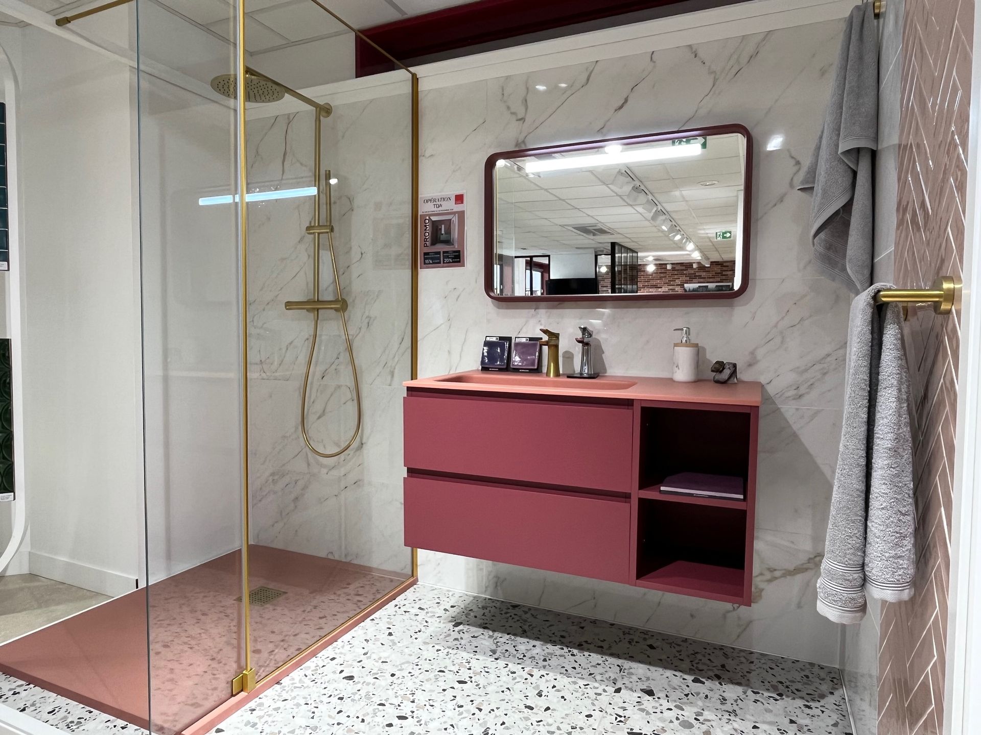 Salle de bain moderne avec vanité rose, douche et murs en marbre.