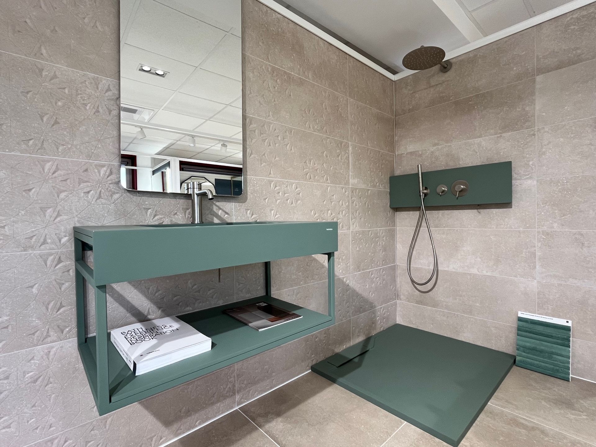 Salle de bain verte avec lavabo mural, pommeaux de douche et tapis de sol assorti. Murs carrelés beiges.