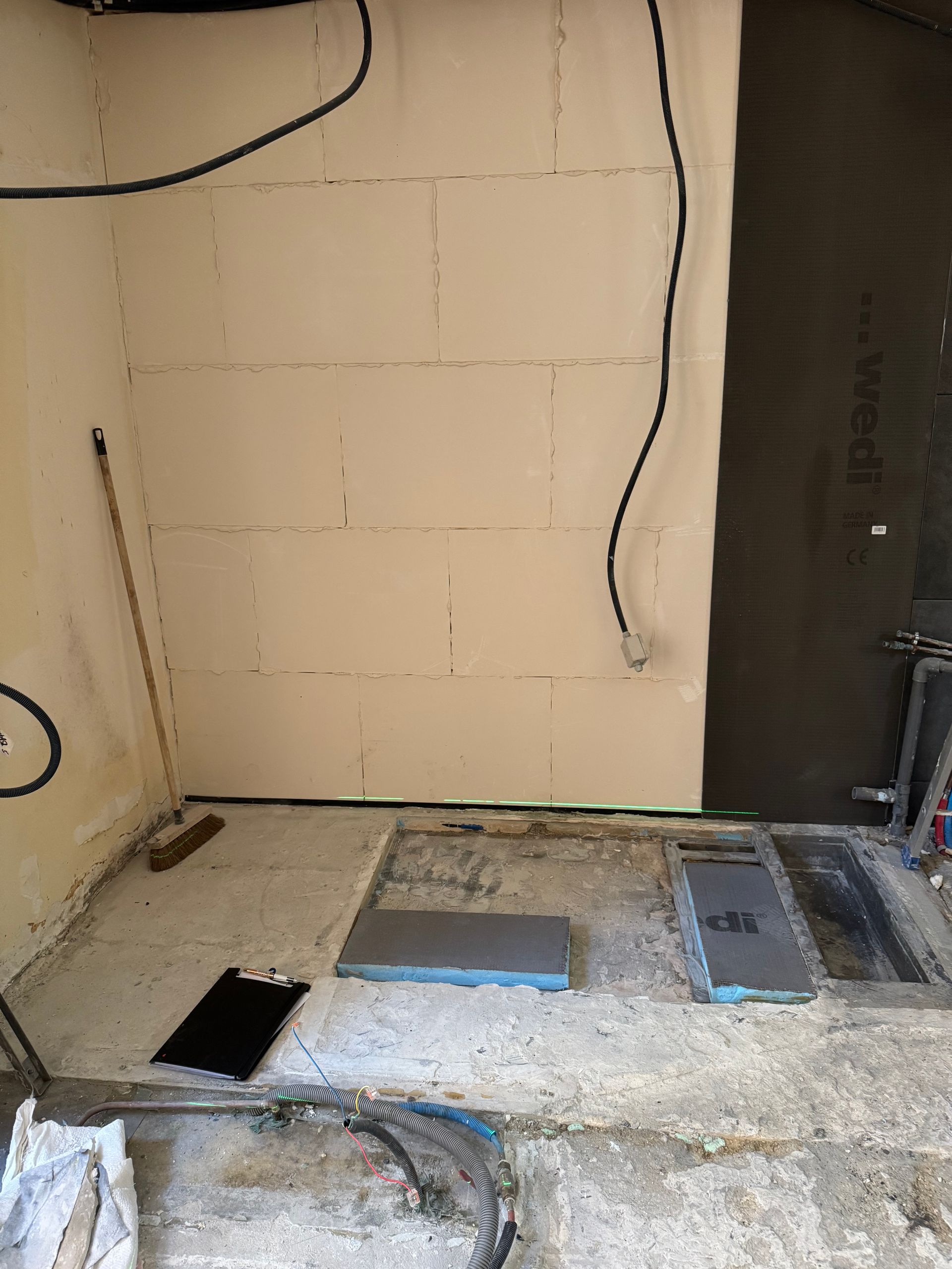 Salle de bain en construction; isolation des murs, plancher exposé et câblage électrique.