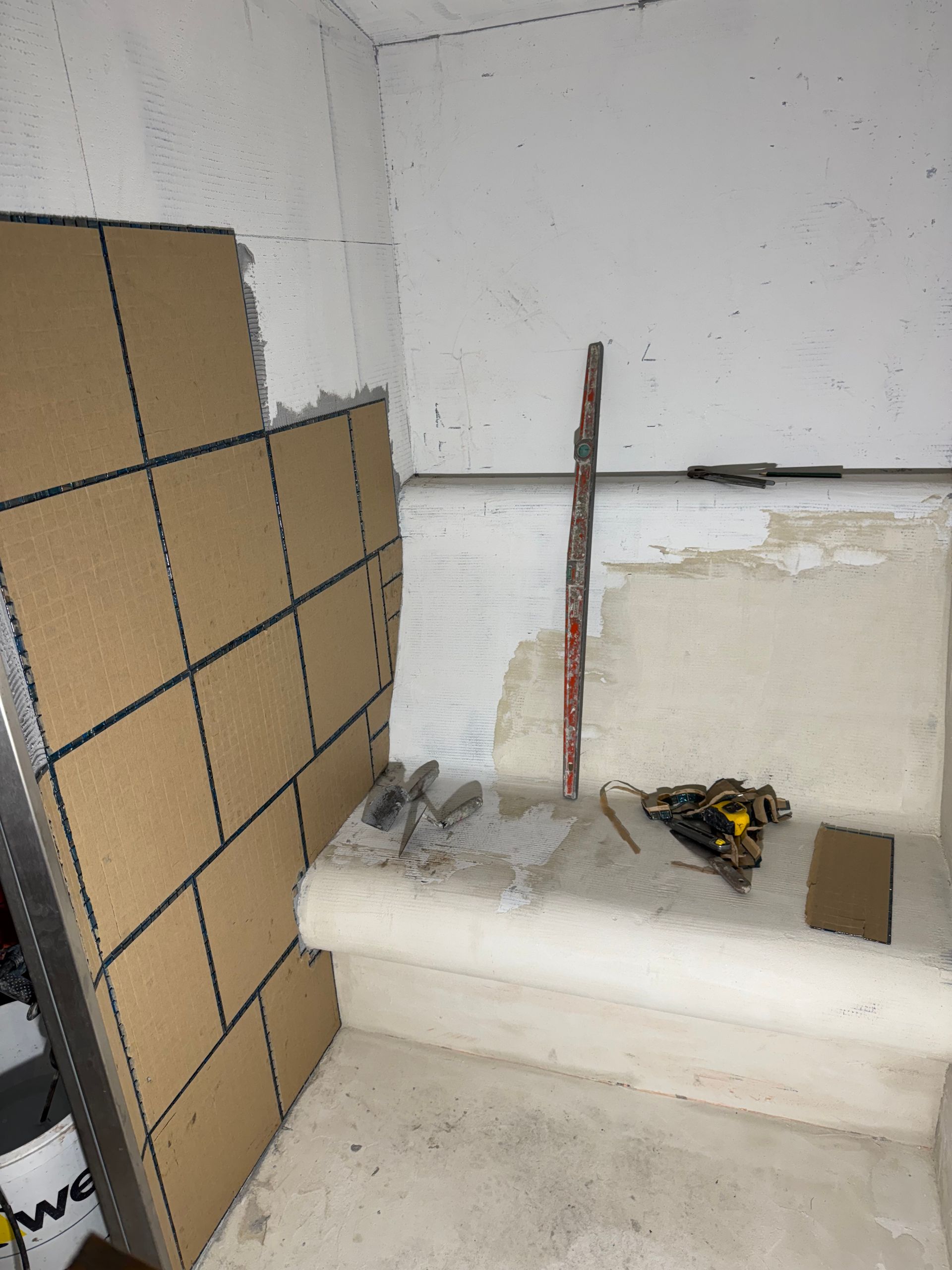 Chantier de construction avec panneaux muraux beiges et outils. Marches en ciment dans un coin.