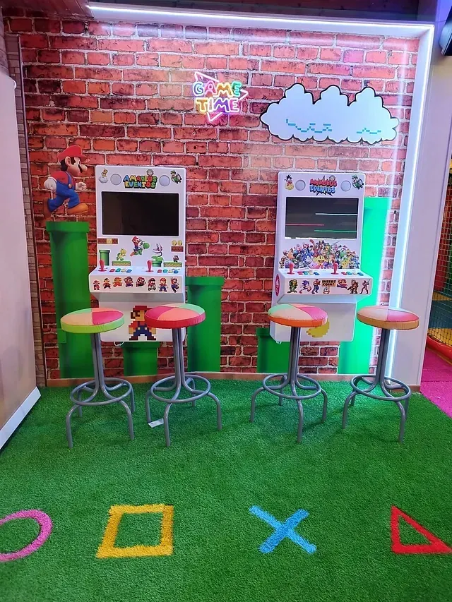 Una habitación con dos máquinas de videojuegos y una pared de ladrillos.
