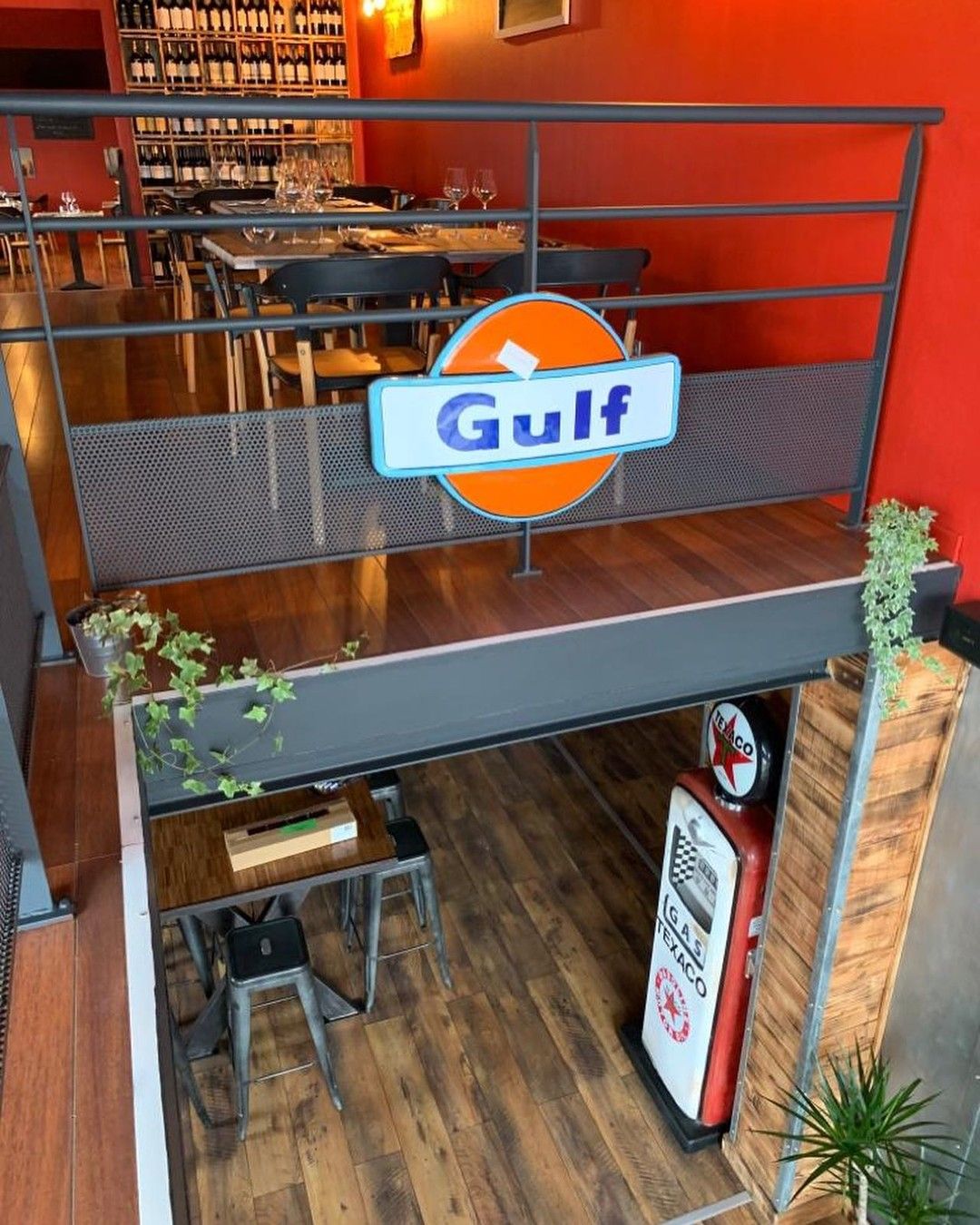 Intérieur de restaurant avec enseigne Gulf, parquet, tables et une pompe à essence vintage.