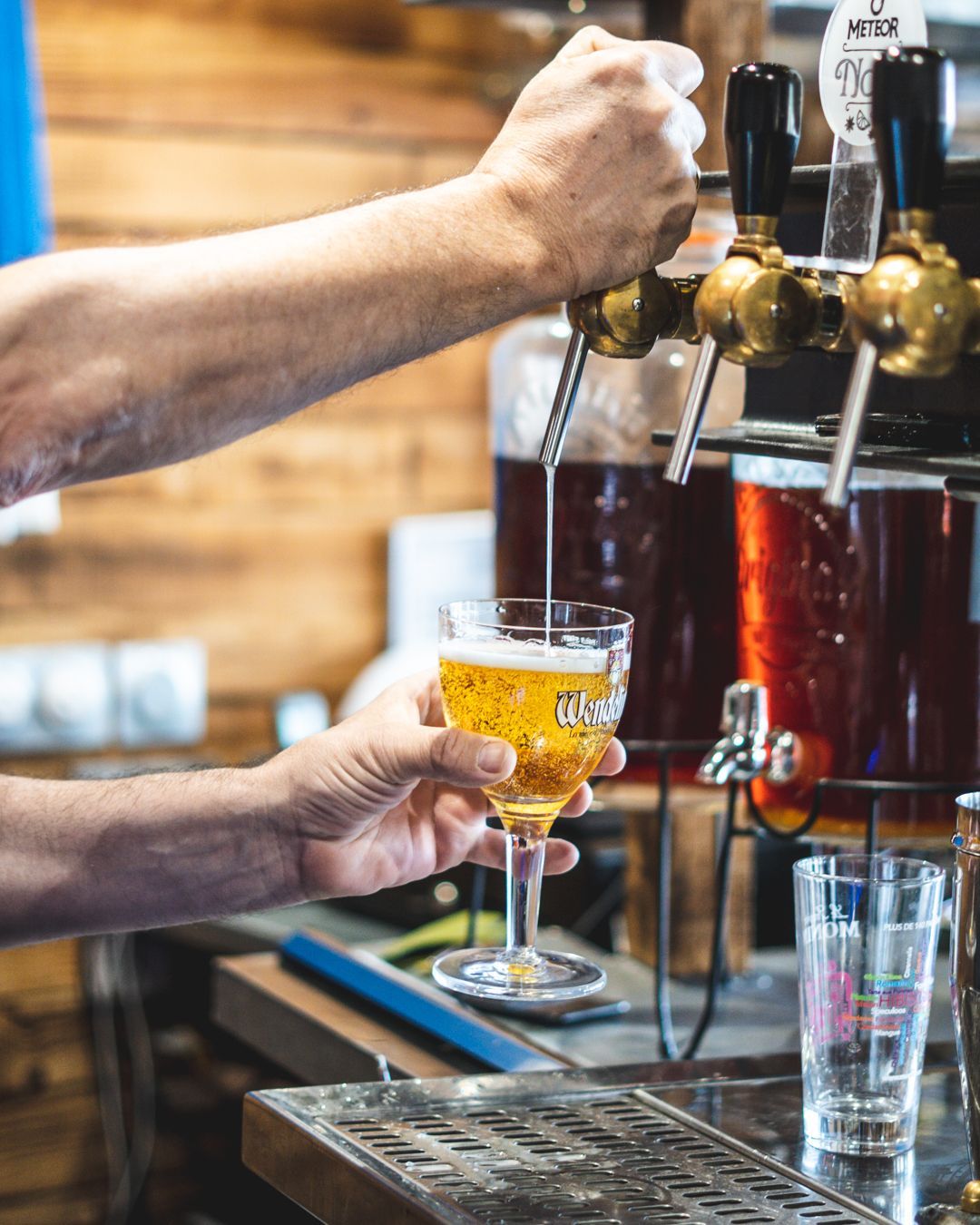 Un barman verse une bière pression dans un verre à pied, dans un bar.