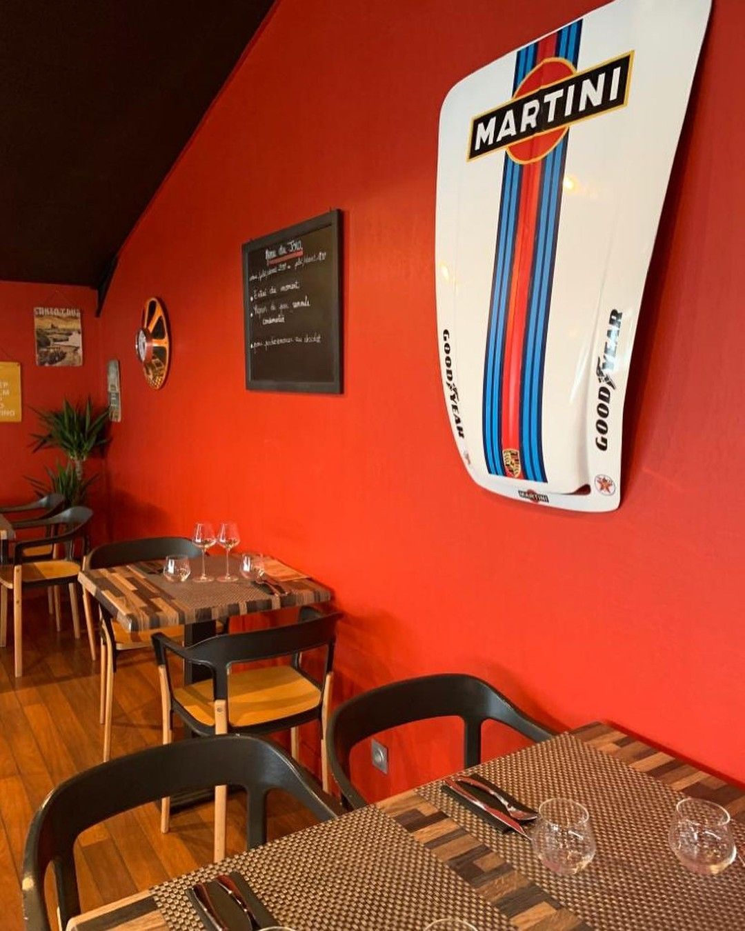Intérieur du restaurant avec murs rouges, parquet et tables dressées pour le repas.