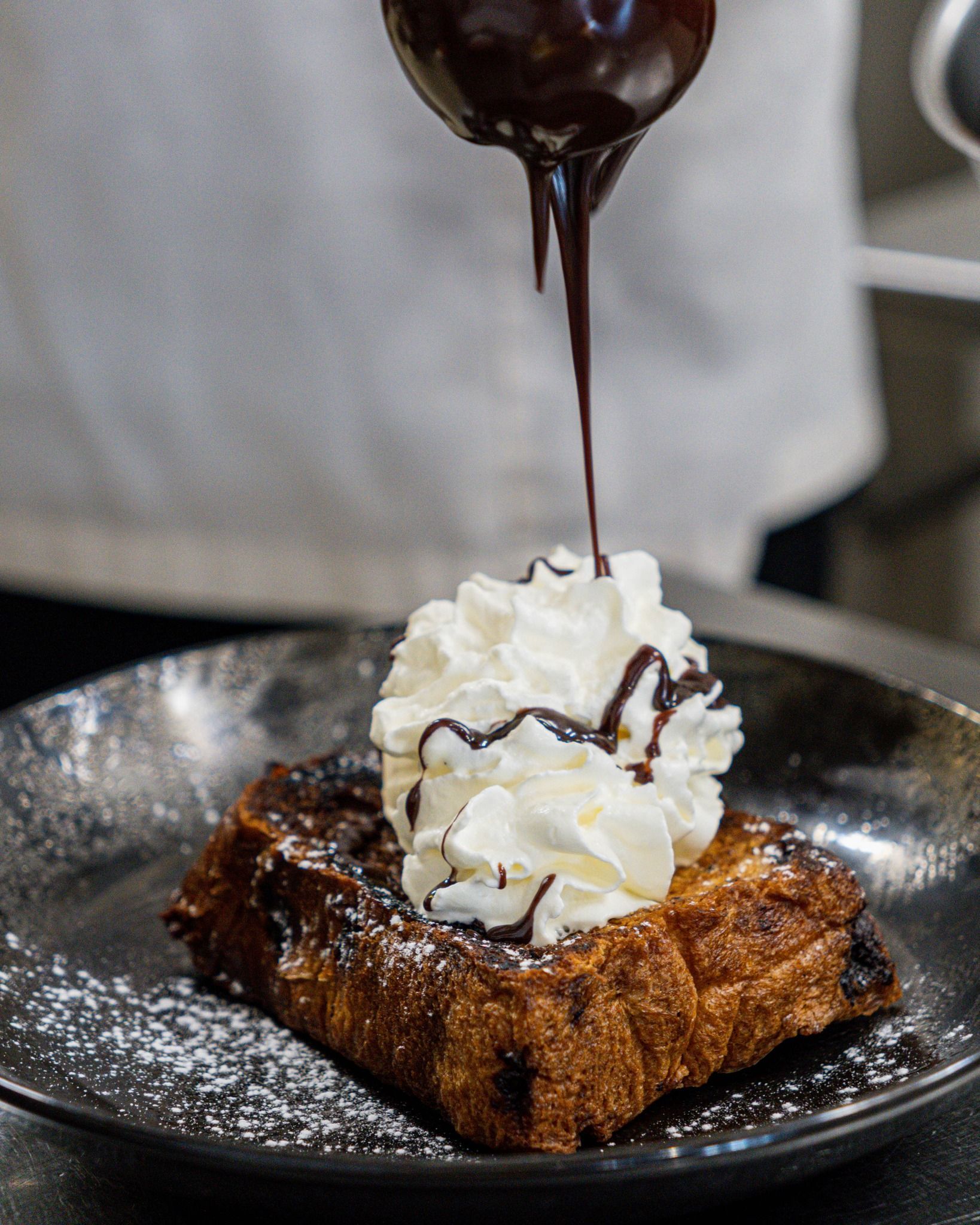 Sauce au chocolat nappant de crème fouettée sur un pouding au pain et aux pépites de chocolat.