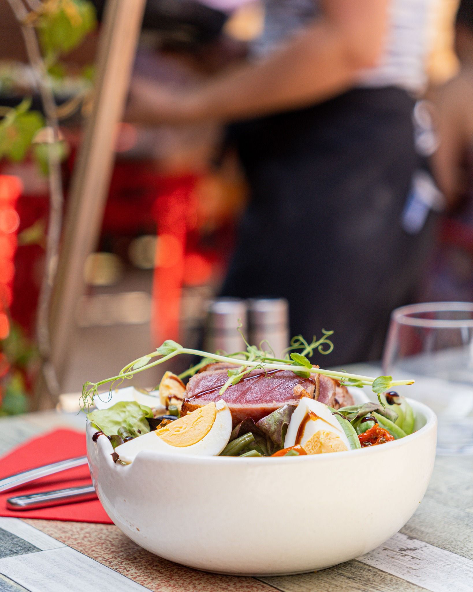 Salade composée d'un œuf et de thon saisi, posée sur une table de restaurant.
