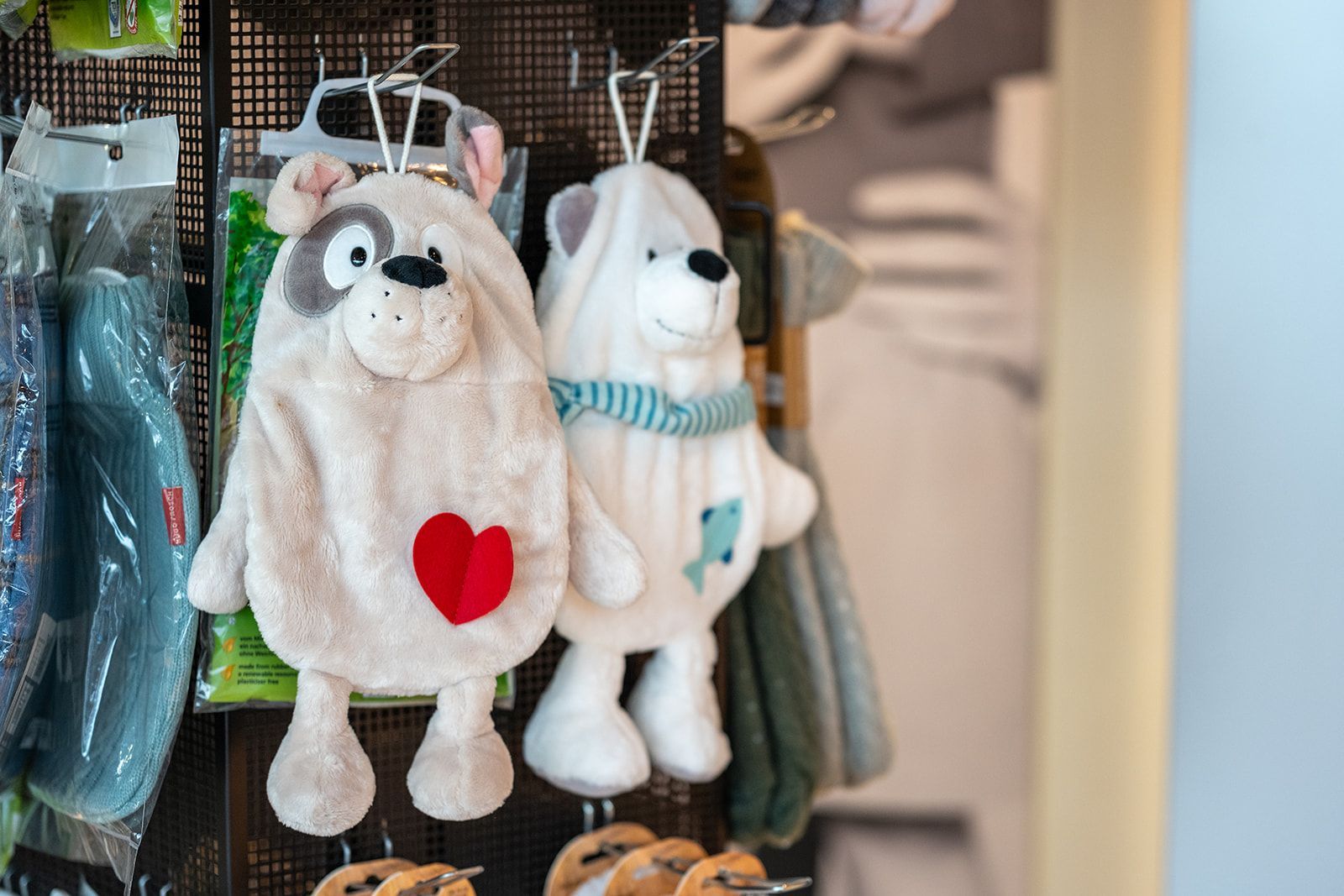 Zwei Plüschhandtücher in Tierform hängen ausgestellt; eines hat ein Herz, das andere einen blauen Schal.