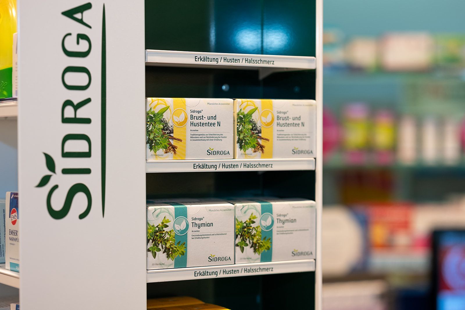 Regalaufsteller in einer Apotheke mit Teekartons und dem Sidroga-Logo.