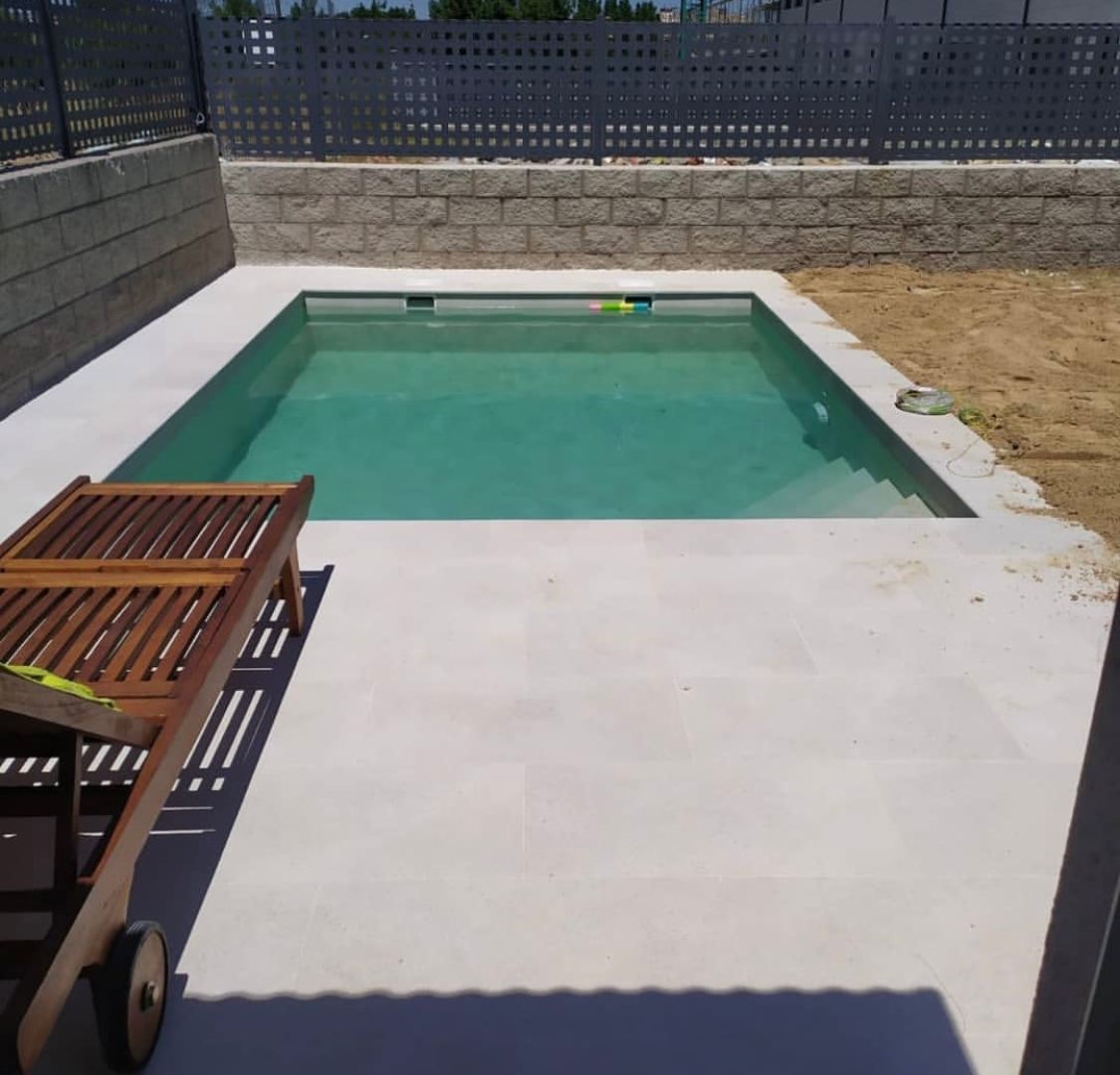 Una silla de madera se encuentra junto a una gran piscina.