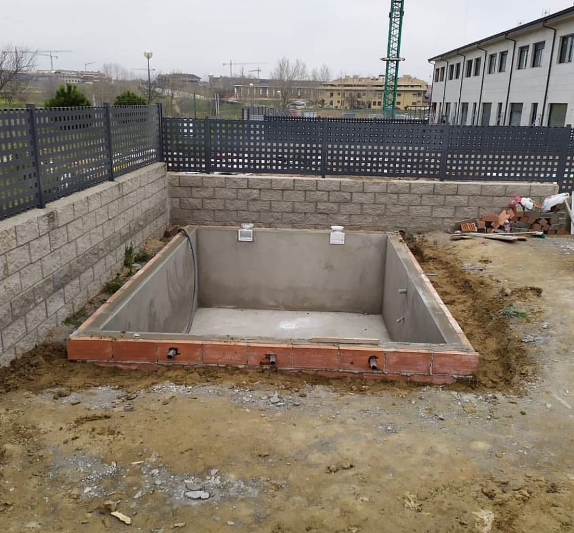 Se está construyendo una gran piscina de hormigón en un patio trasero.
