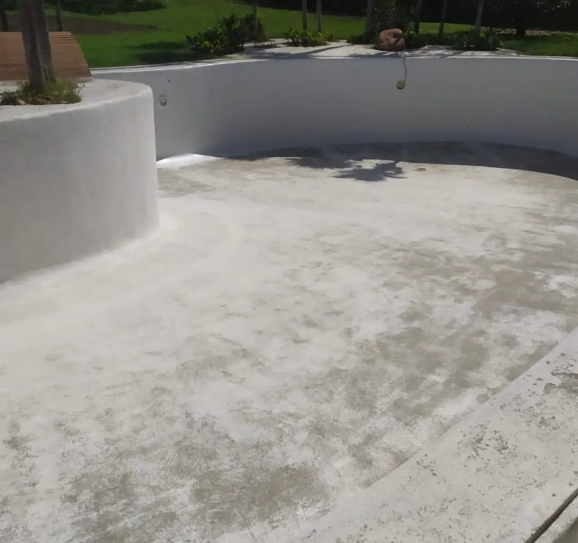 Una gran piscina blanca con suelo de hormigón.