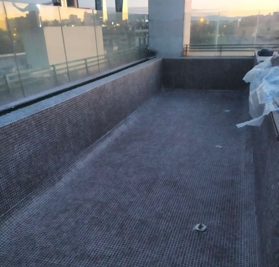 Una gran piscina vacía con un edificio al fondo.