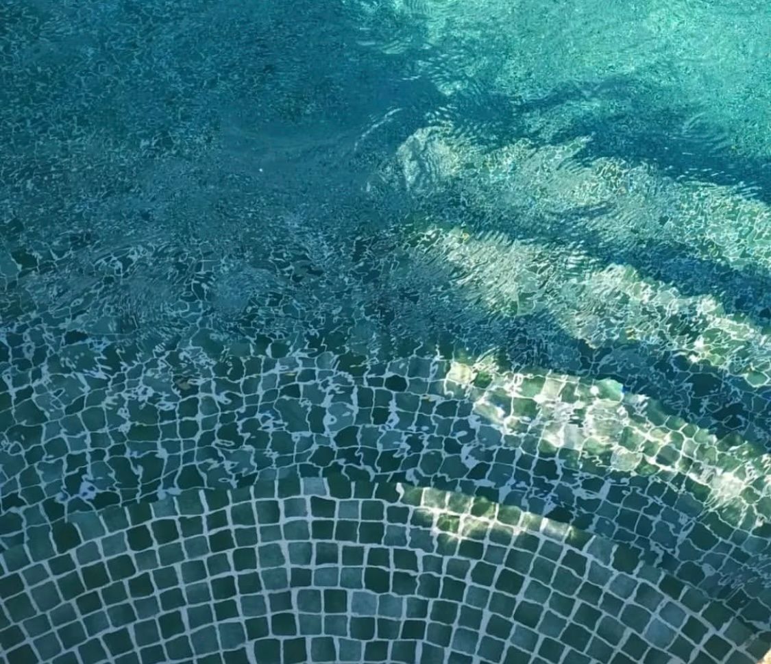 Un primer plano de una piscina con suelo de baldosas azules.