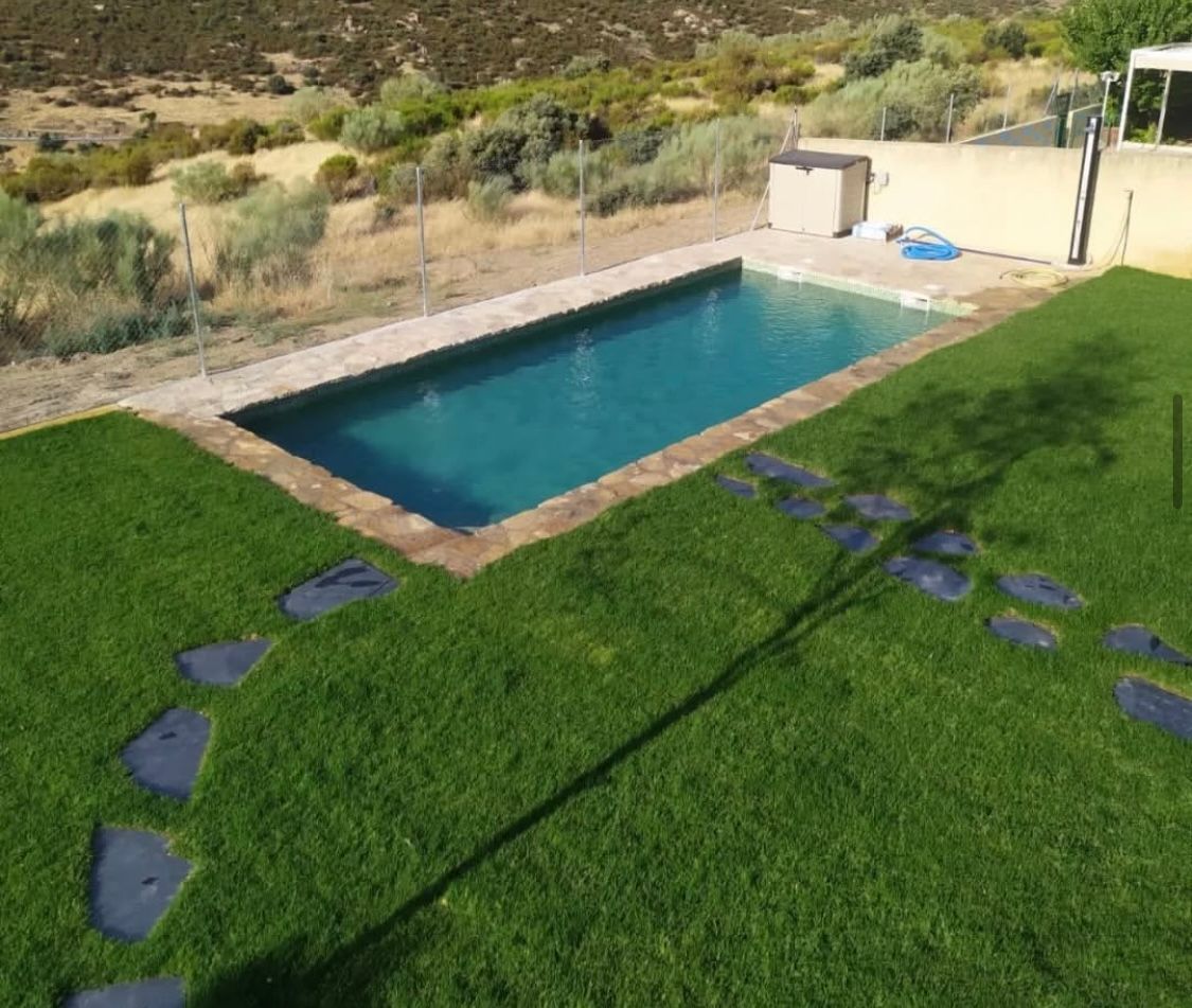Una gran piscina está en medio de un exuberante césped verde.