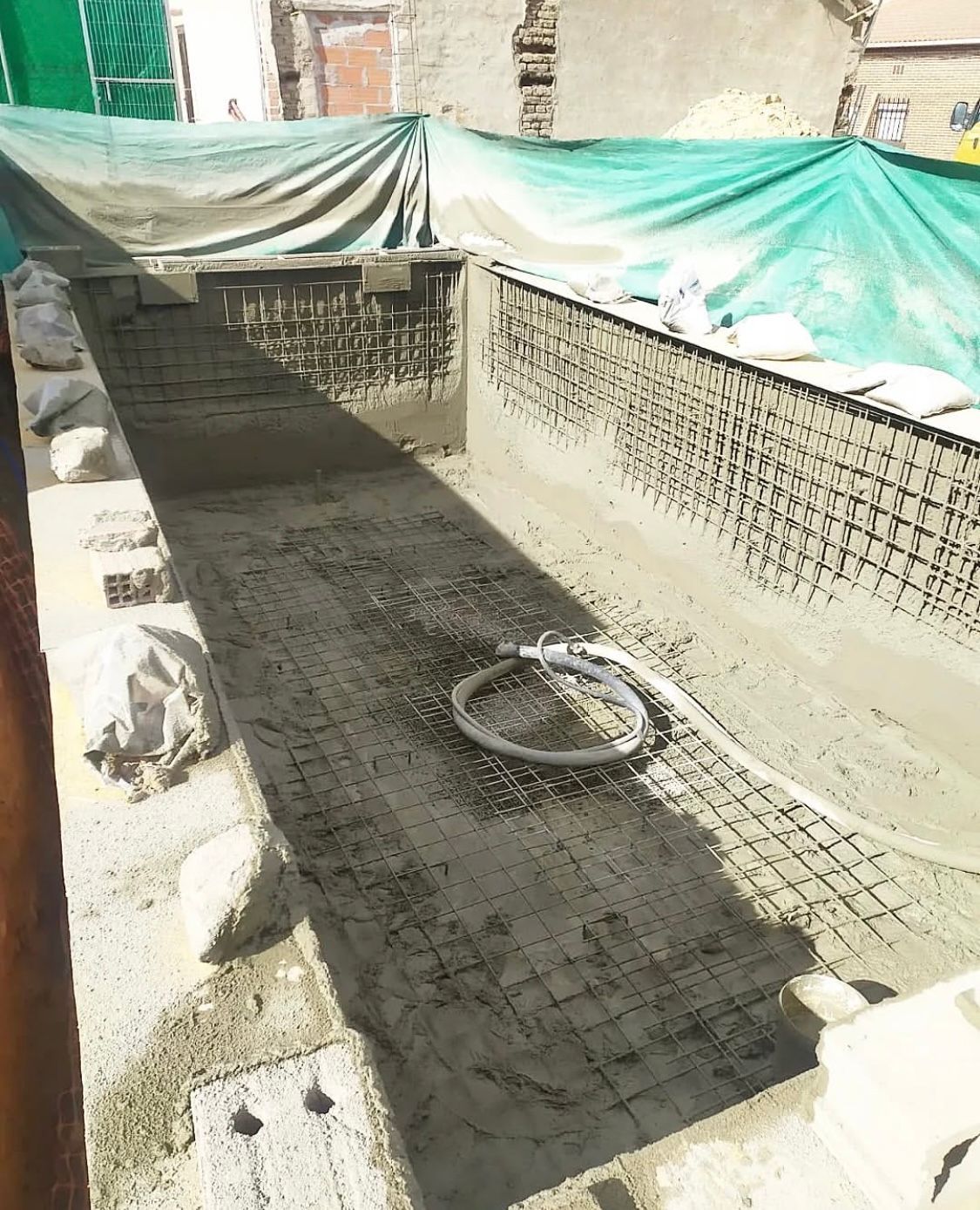 Una manguera está tendida en el suelo al lado de una pared de ladrillos.