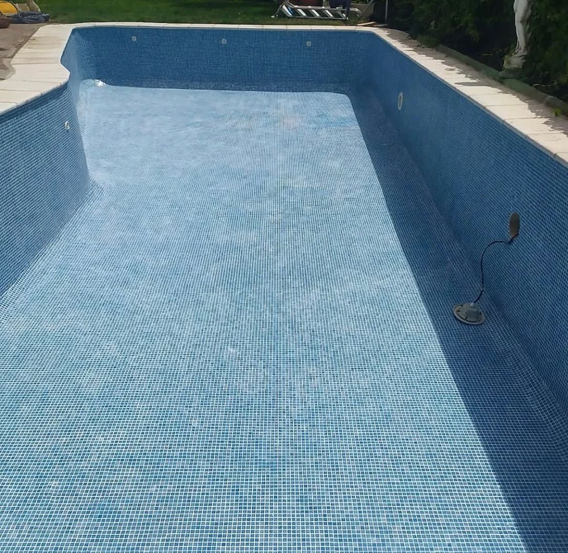 Una gran piscina con azulejos azules y borde blanco.