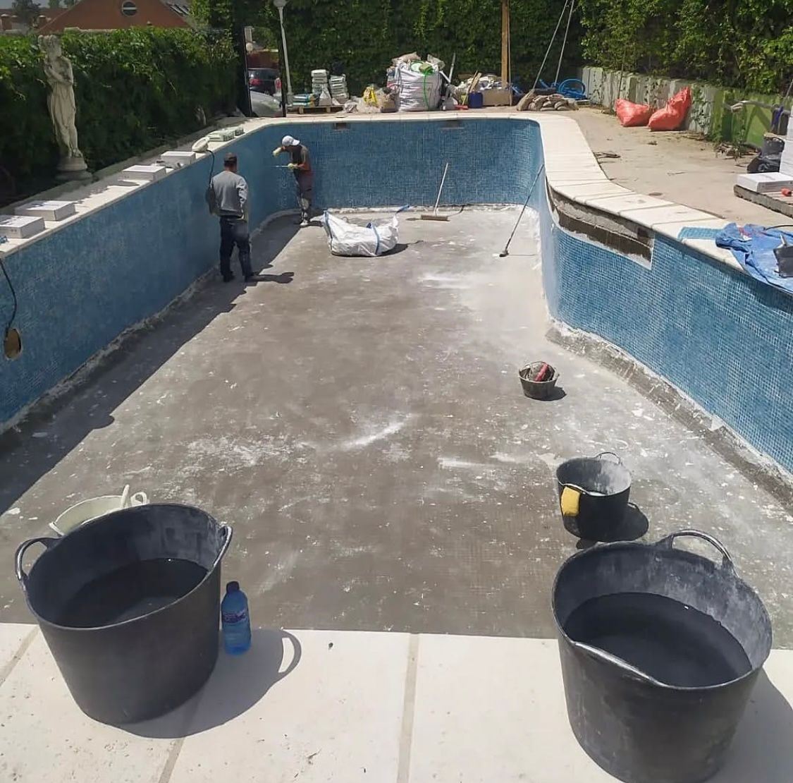 Dos cubos de agua están sentados frente a una piscina.