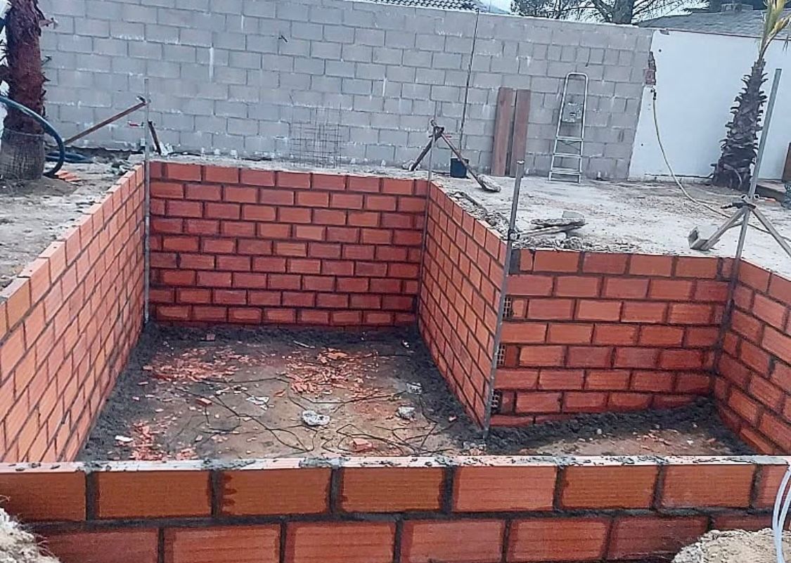 Se está construyendo un gran muro de ladrillos en un patio trasero.