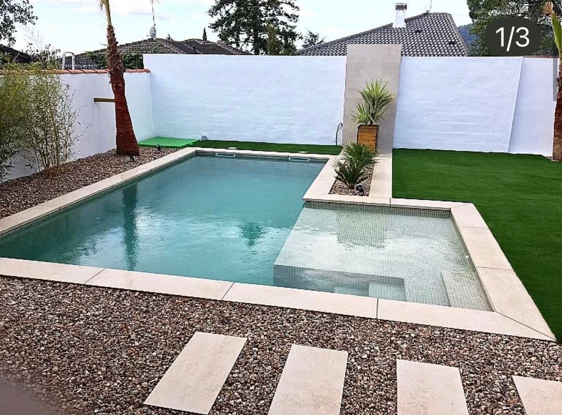 Una gran piscina está rodeada por una valla blanca y césped.