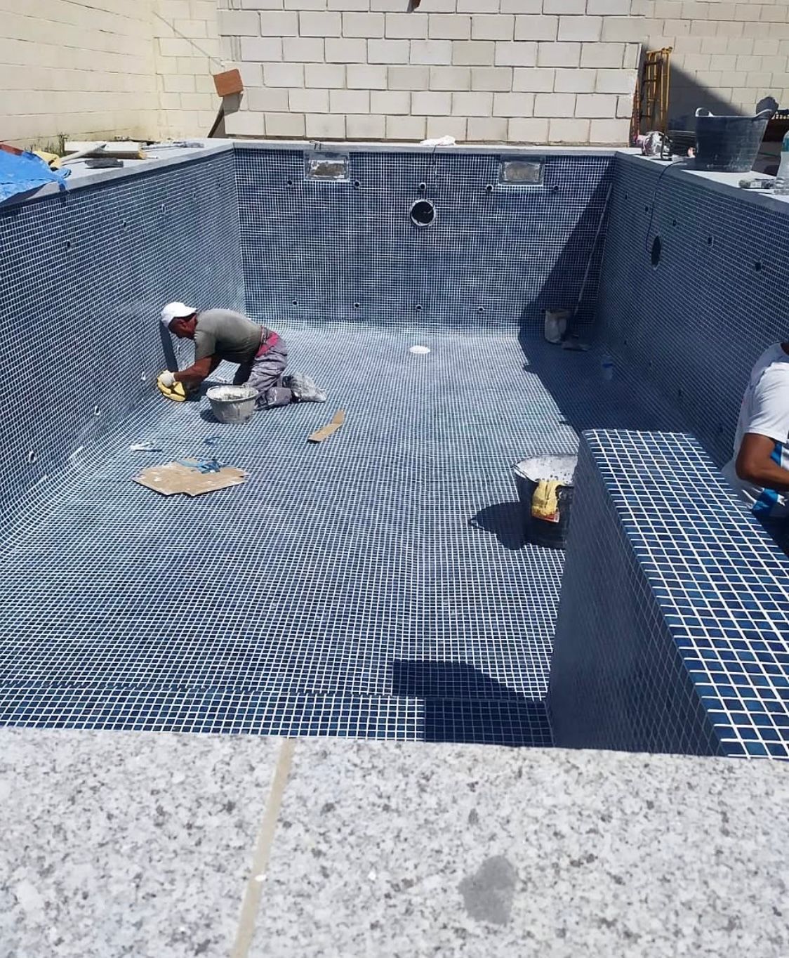 Un hombre está trabajando en el fondo de una piscina.
