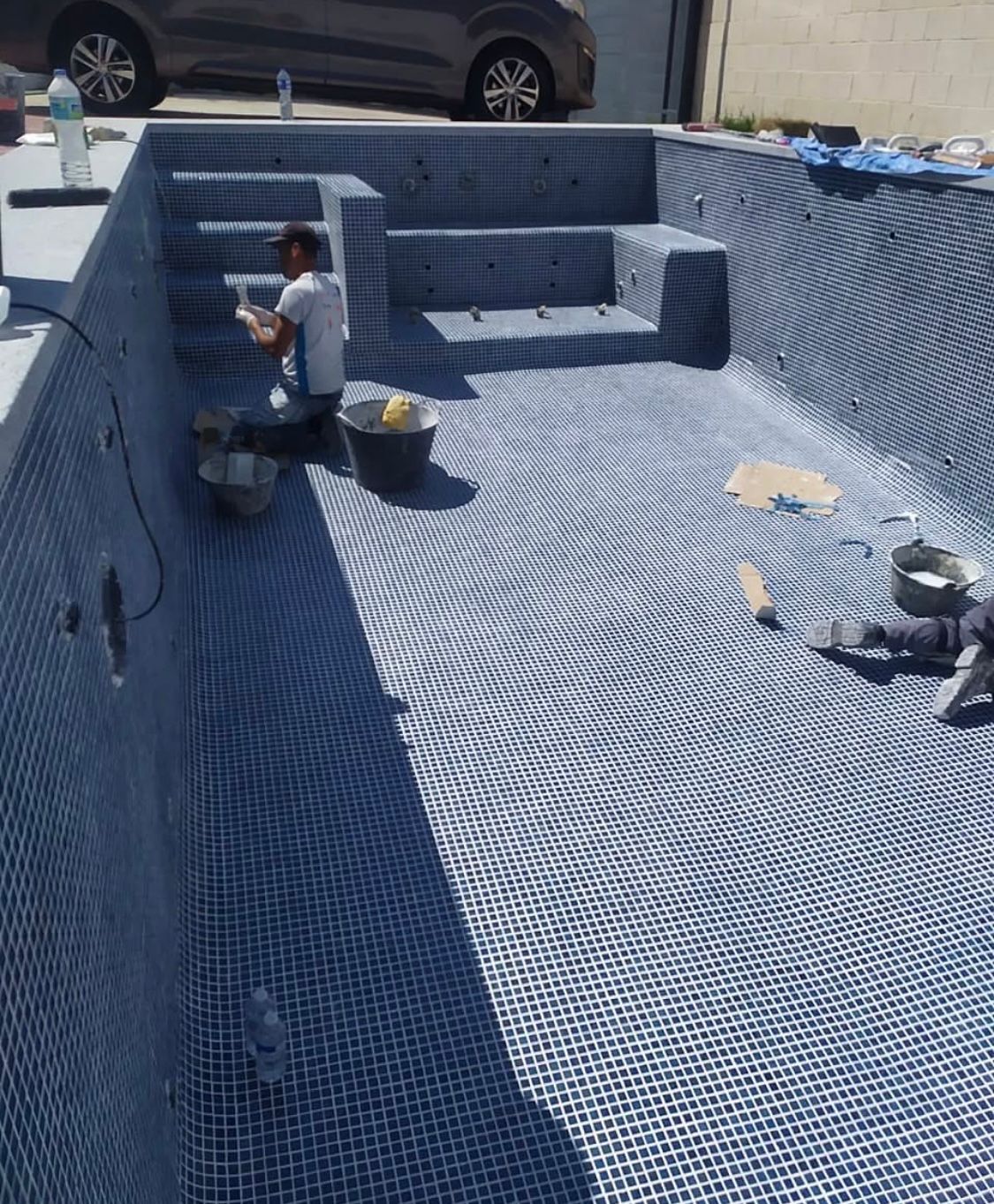 Un hombre está trabajando en el suelo de una piscina.
