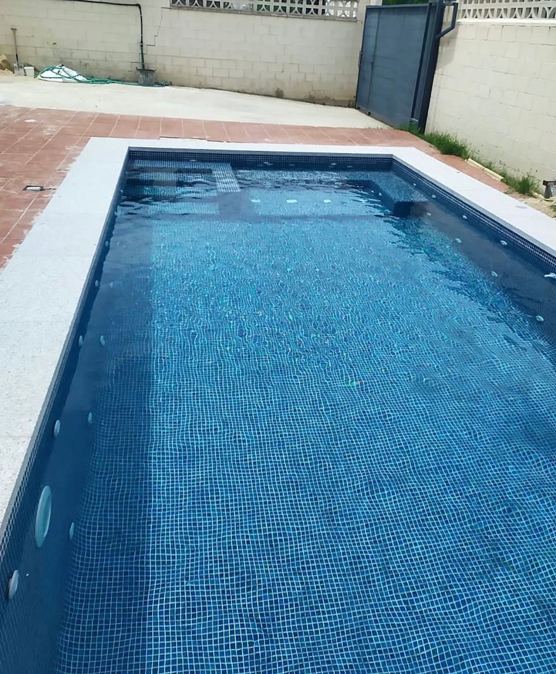 Una gran piscina llena de agua azul en un patio trasero.