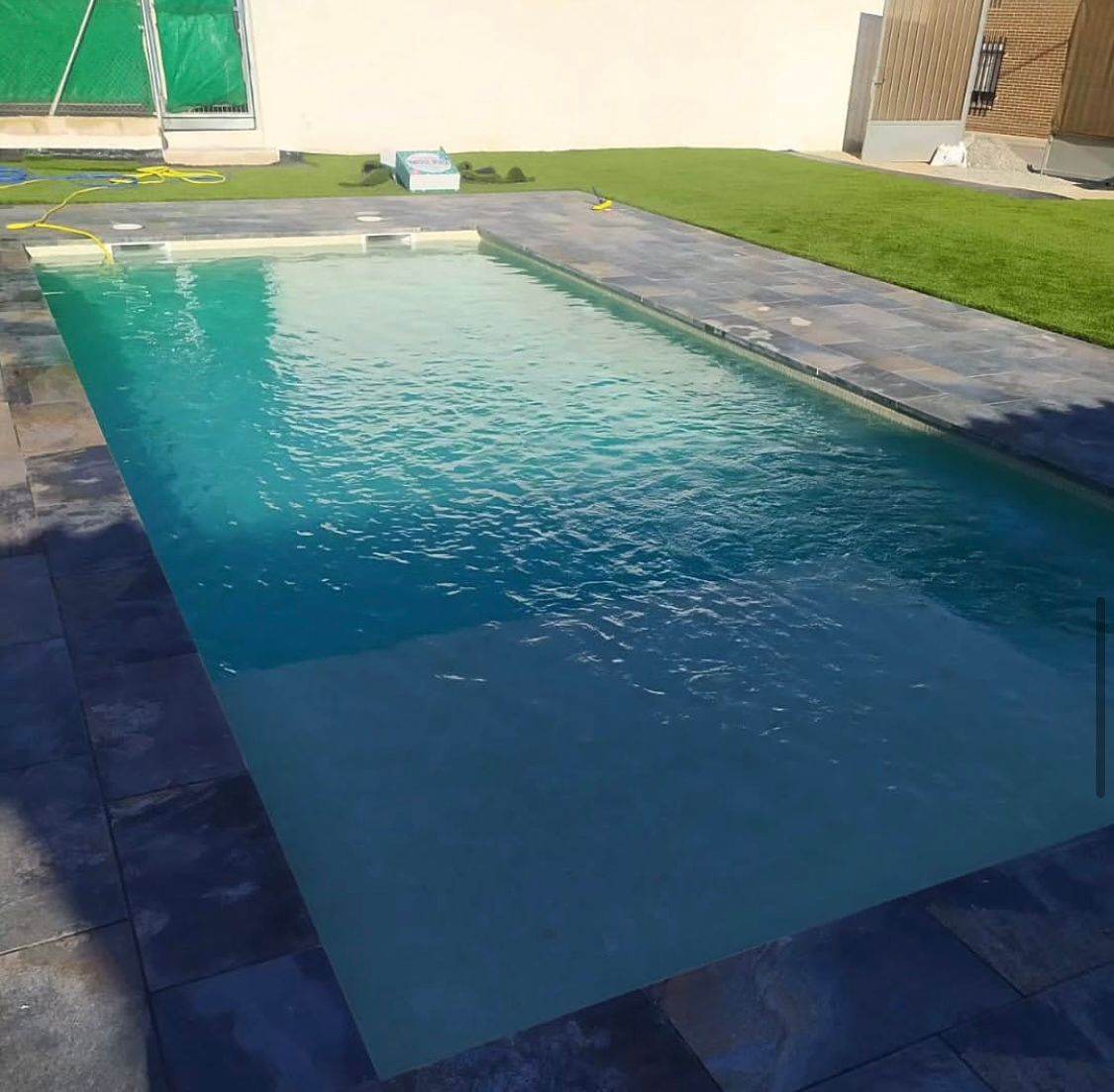 Una gran piscina llena de agua azul en un patio trasero.