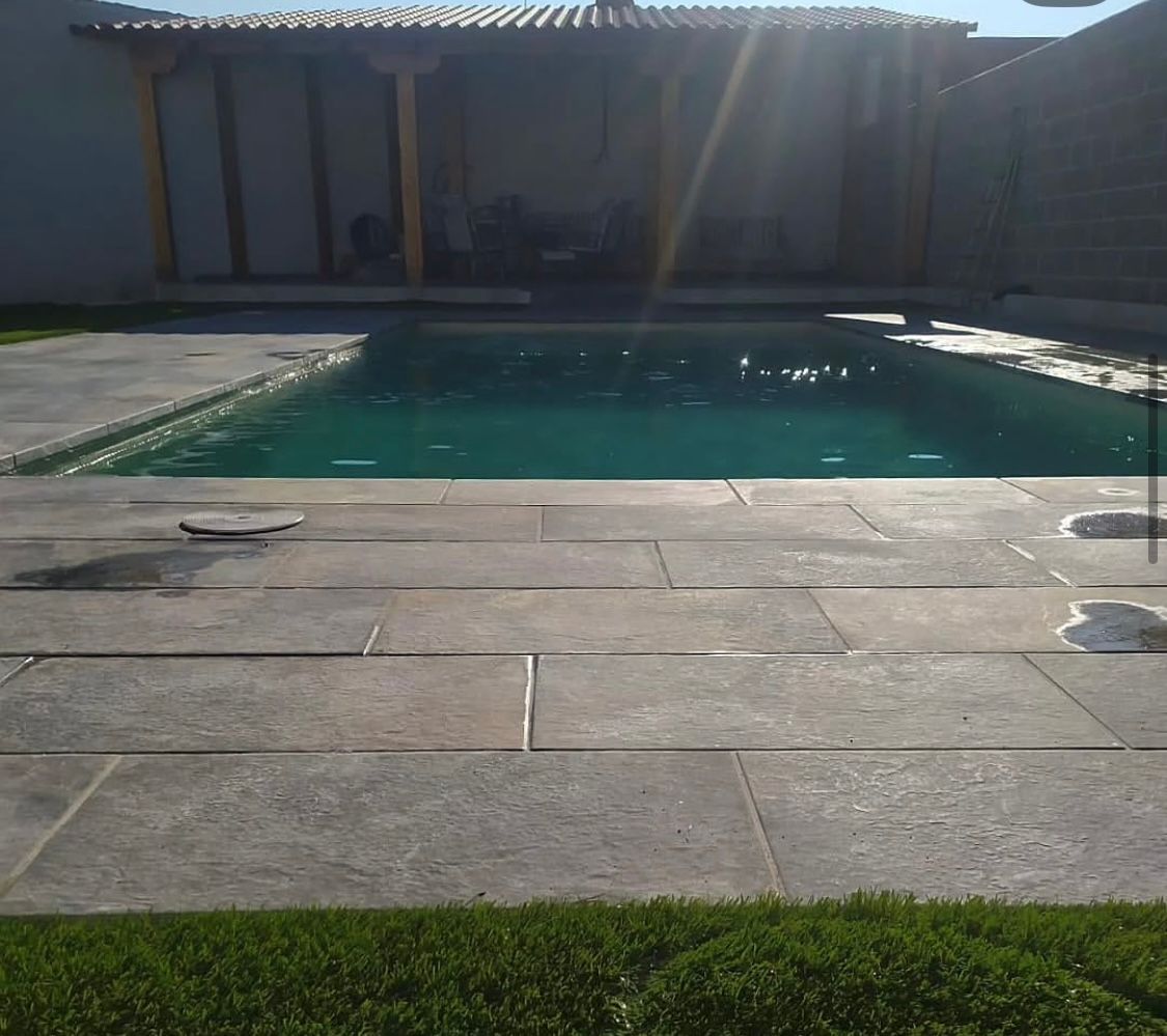 Una gran piscina en un patio trasero con una pérgola sobre ella.