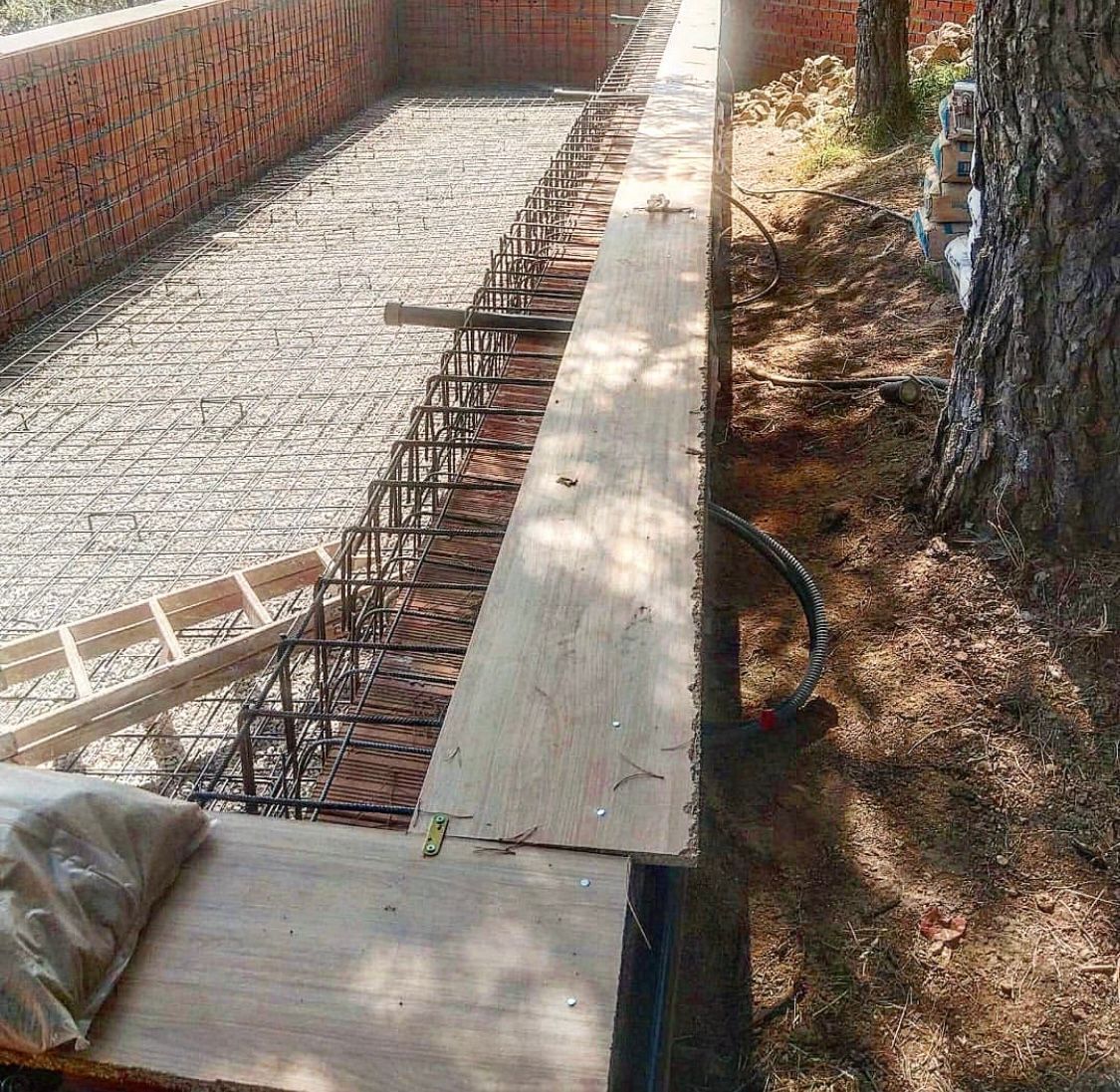 Un banco de madera está sentado al lado de una pared de ladrillos.