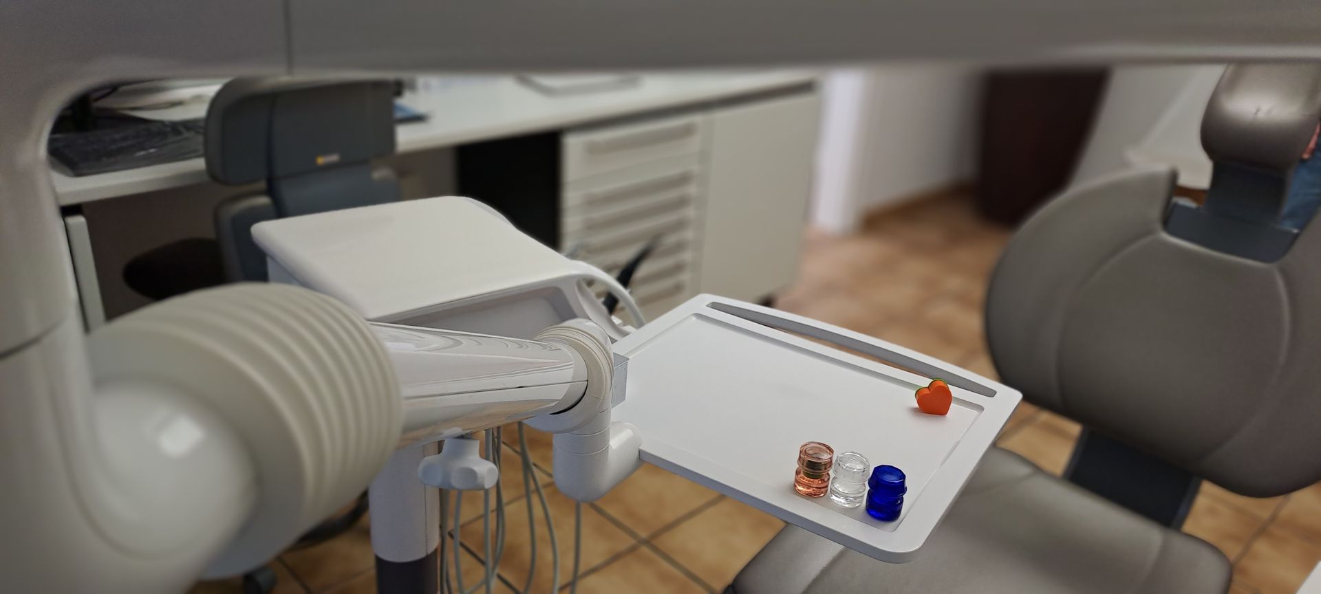 Zahnarztpraxis Grau – ein Zahnarzt untersucht mit einem Spiegel die Rückseite der Zähne einer Patientin.