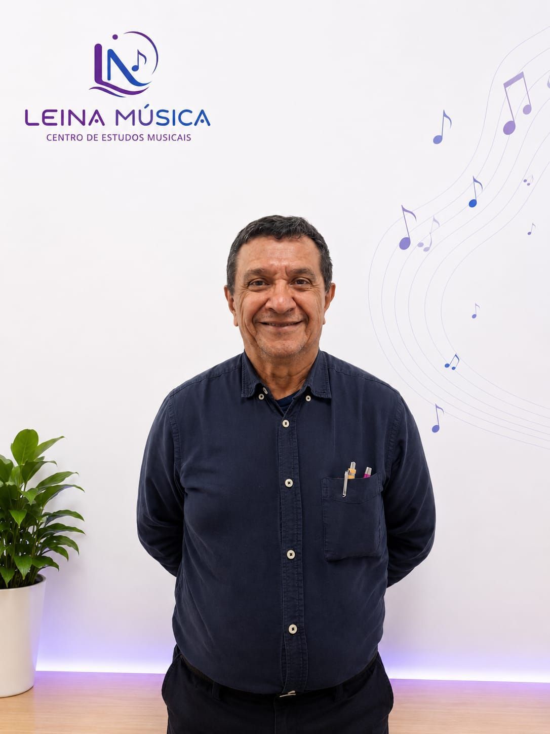 Un hombre de pie frente a un letrero de Leina Música, sonriendo en una habitación blanca