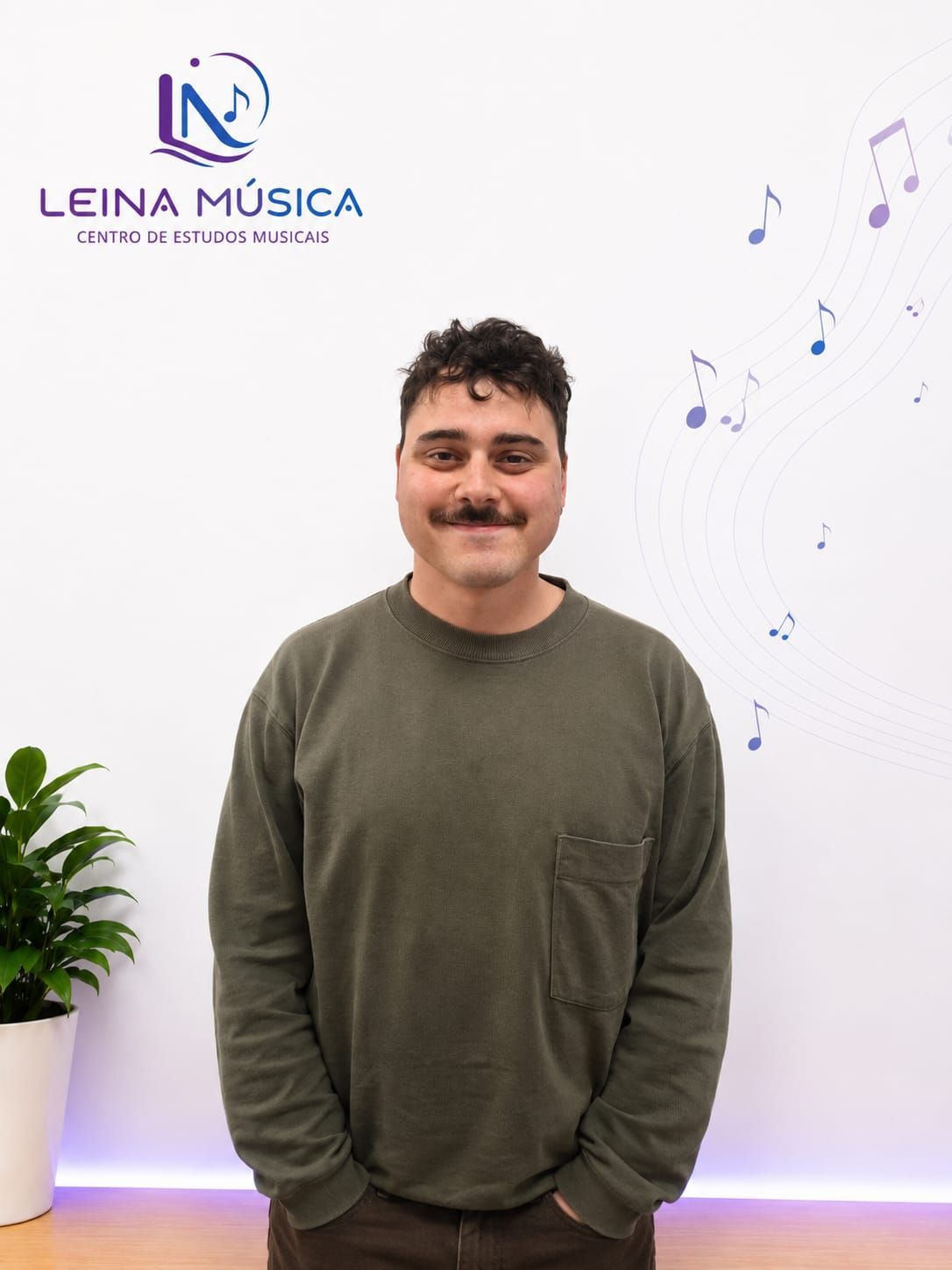 Un hombre, de pie en el interior de una vivienda, frente a una pared con el logotipo de Leina Música