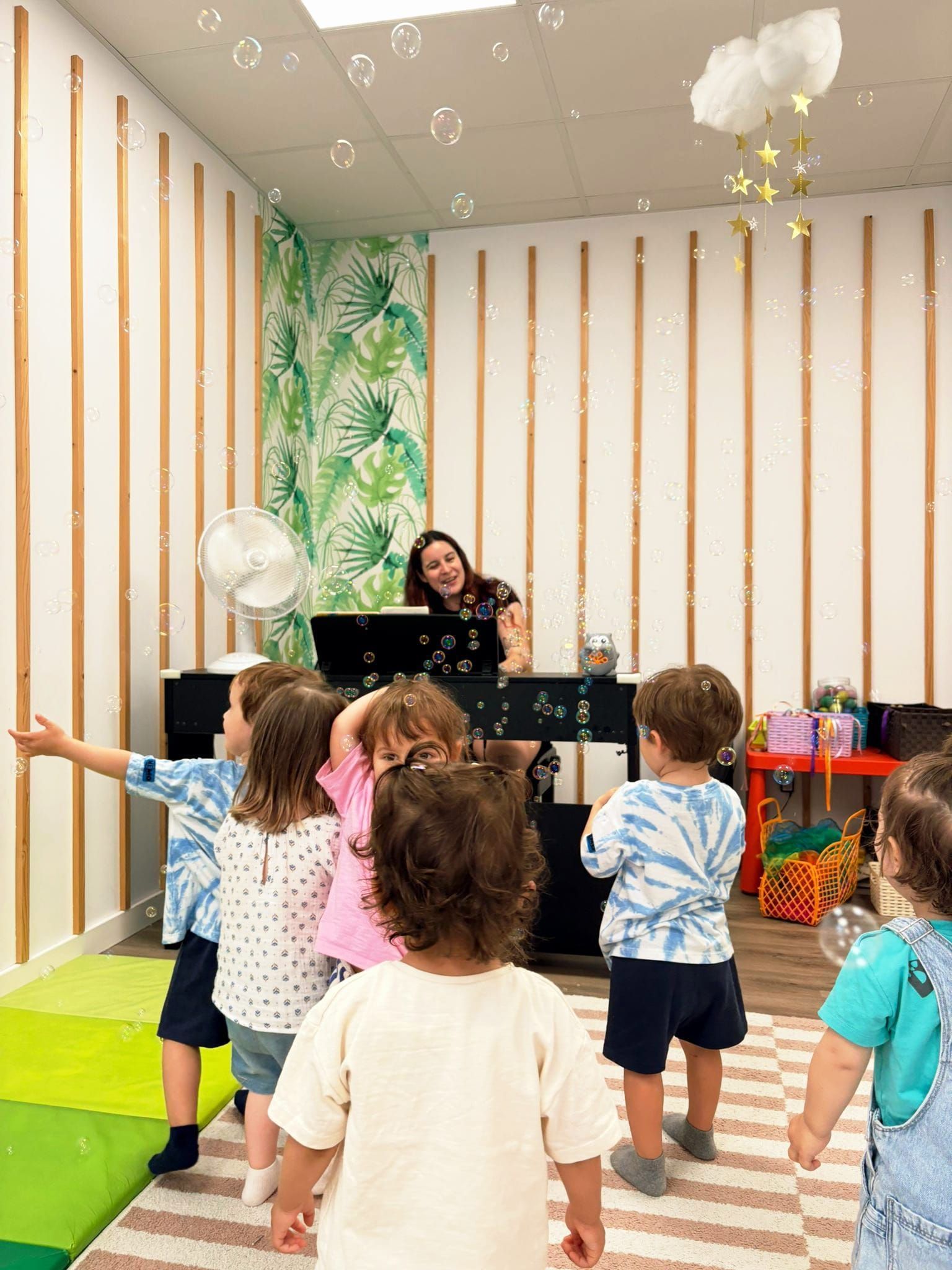 Hora del cuento con niños sentados en alfombras coloridas mientras un adulto les muestra un instrumento