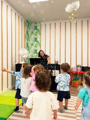 Hora del cuento con niños sentados en alfombras coloridas mientras un adulto les muestra un instrumento