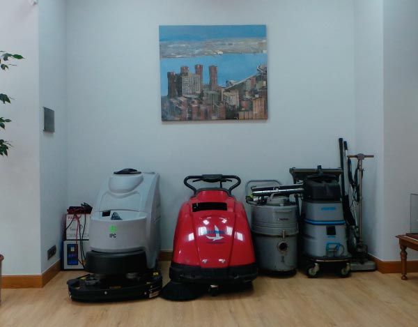 Varias aspiradoras están alineadas en una habitación con una pintura en la pared encima de ellas.