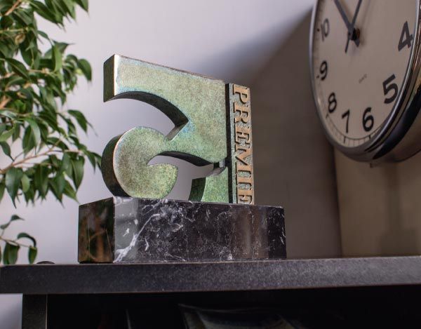 Un reloj en un estante con una estatua delante de él.