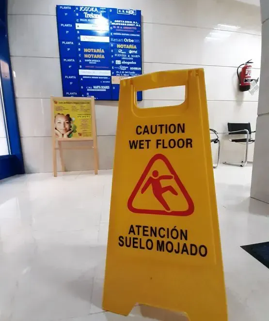 Un cartel amarillo que dice precaución piso mojado atención suelo mojado