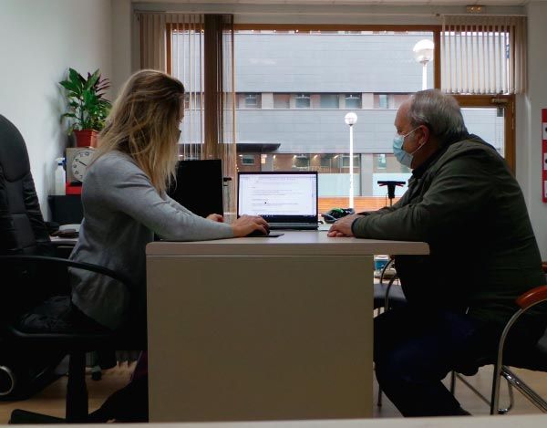 Un hombre y una mujer están sentados en un escritorio con una computadora portátil.