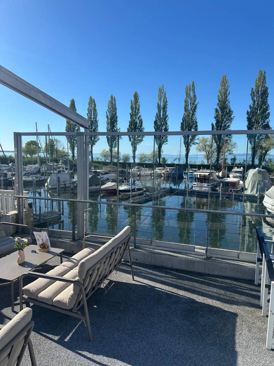 Hafen mit Booten, Liegeplätzen und einer Holzbank an einem sonnigen Tag