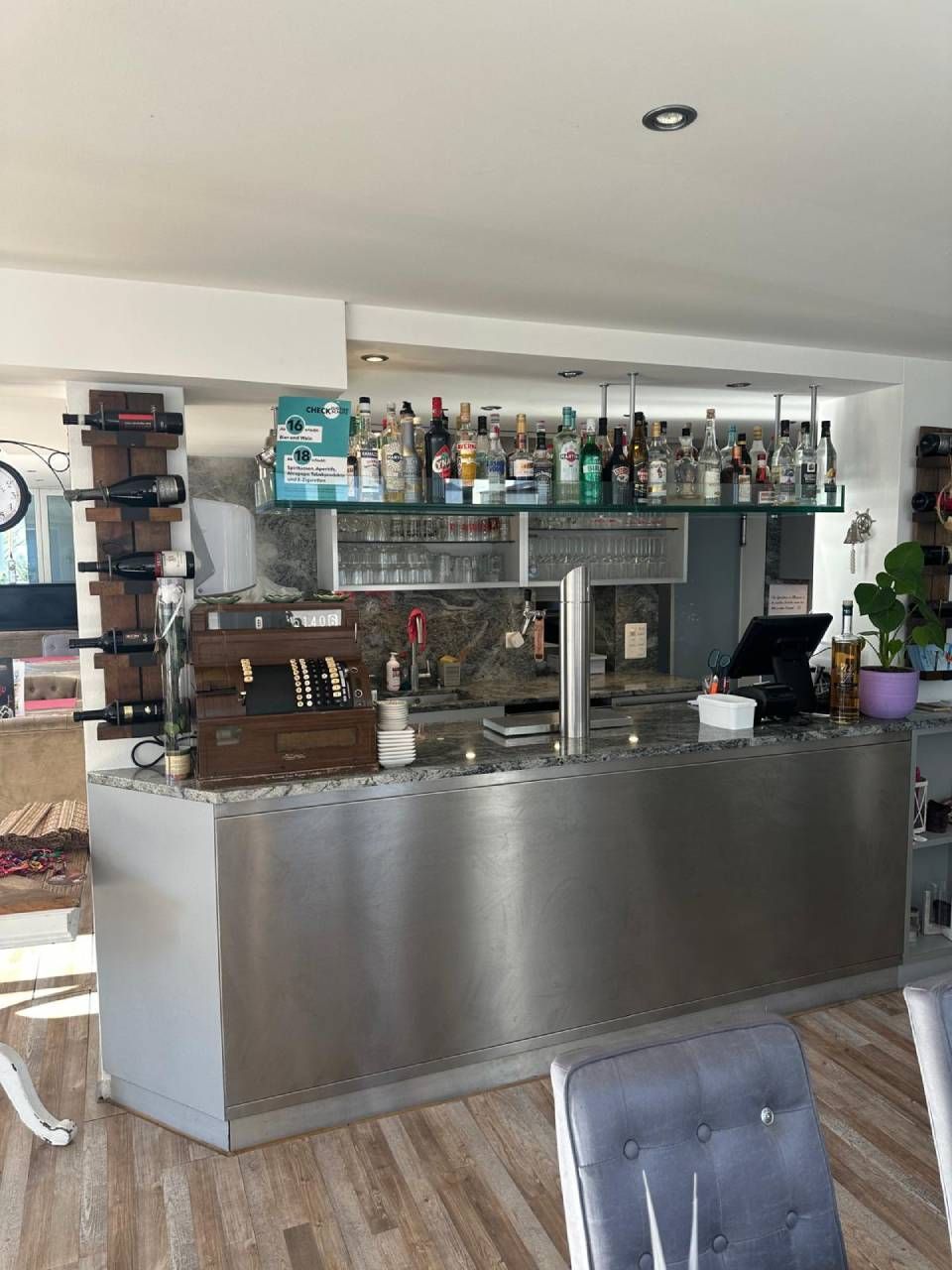 Moderne Bartheke mit Regalen voller Spirituosenflaschen und einer Kaffeemaschine in einem hellen Café-Interieur